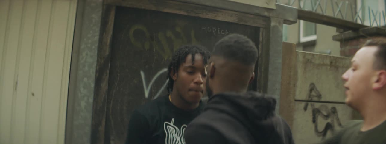 A man walks up to another man on a street and starts fighting him and two others step in to stop it