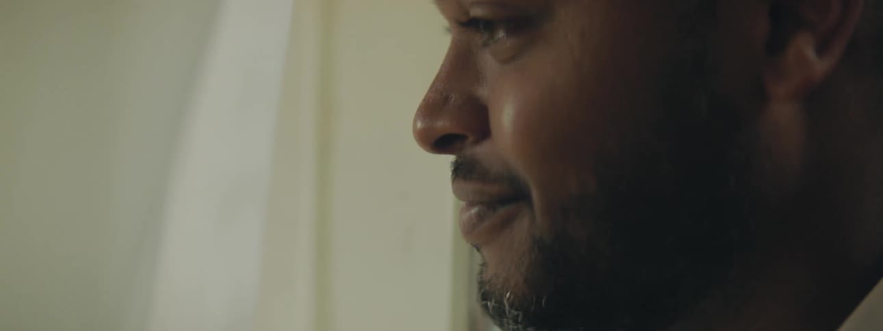 A man looks out the window as tears fall from his eyes