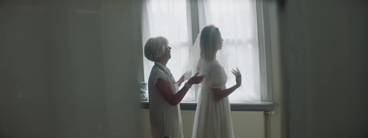 A woman helps another woman straighten her bridal veil