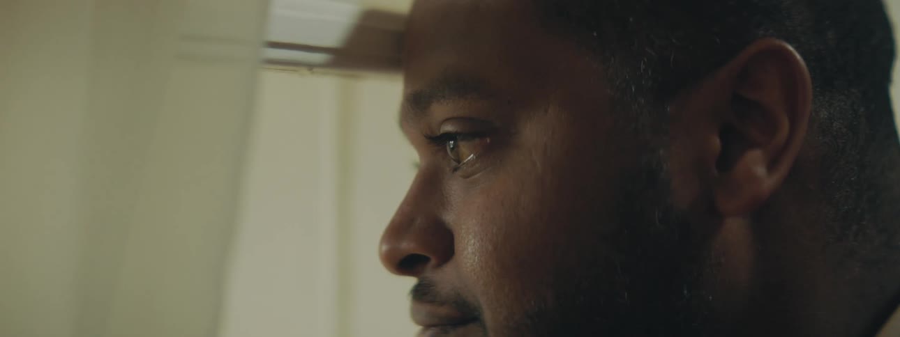 A man looks out his window and smiles and blows a kiss