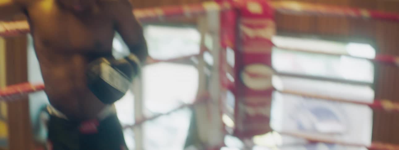 Two men in a boxing ring with boxing gloves boxing in a gym