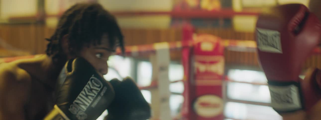 Two men spar in boxing ring in gym near open window