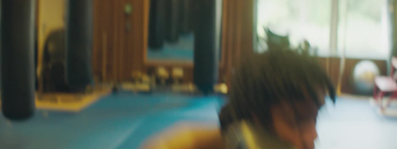 A man with boxing gloves in a gym practicing boxing with windows and a mirror in the background