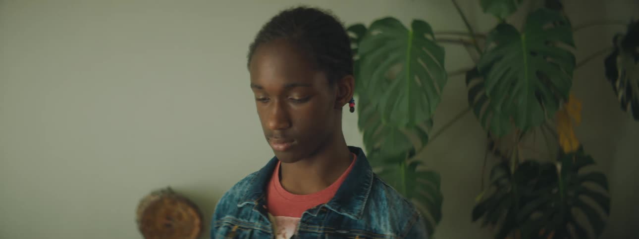 A teenage boy sitting at home with his eyes lowered to the ground