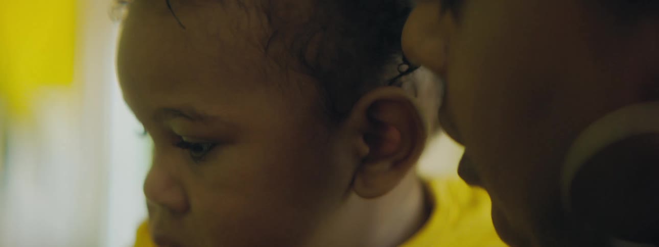 Mother with hoop earrings holds toddler girl with yellow clothes