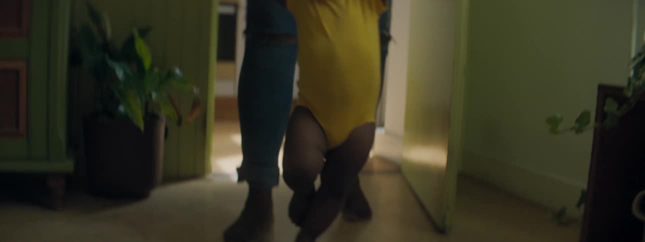 A woman helps a toddler walk into the room