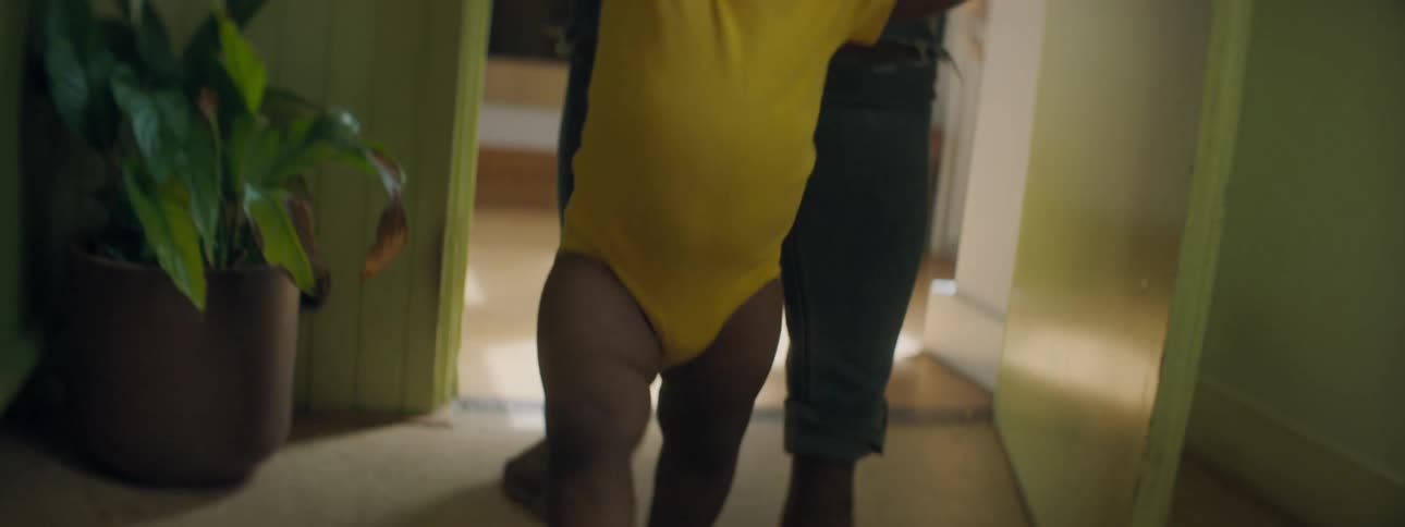 An adult holds on to a babys hands and helps the baby to walk around the home