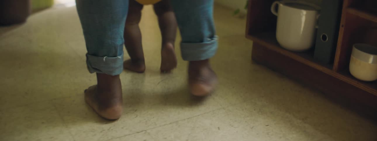 A mother helps her baby walk through the house