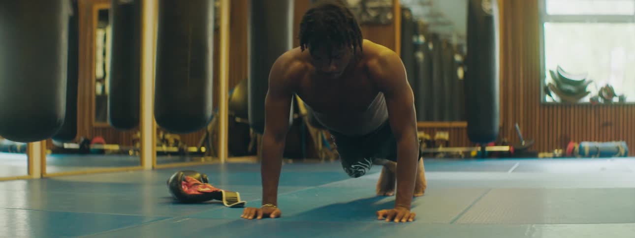Man with braids and shorts does push ups in the gym