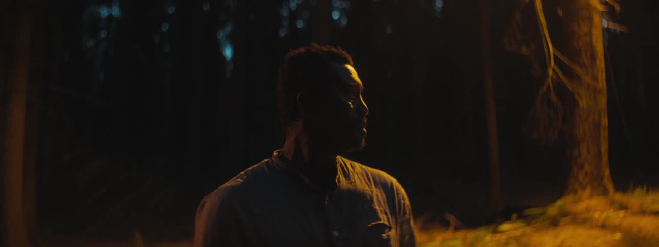Depressed man with a shirt stands in the middle of the road looks around in the forest