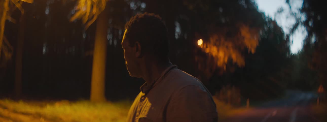 Depressed man with a shirt stands in the middle of the road looks around in the forest