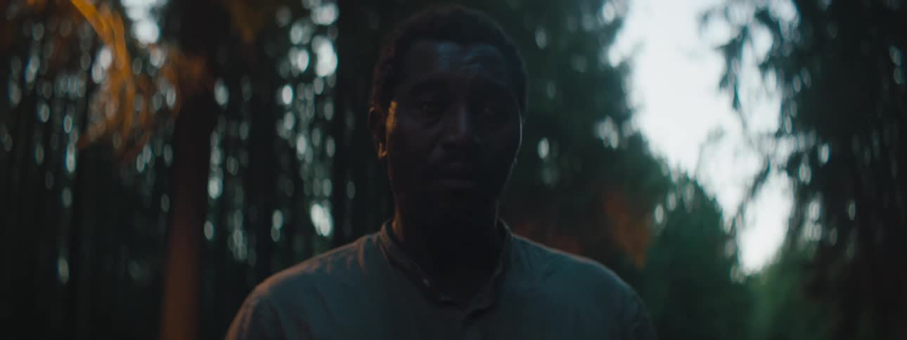 Depressed and sad man with a shirt stands in the middle of the road looks around in the forest