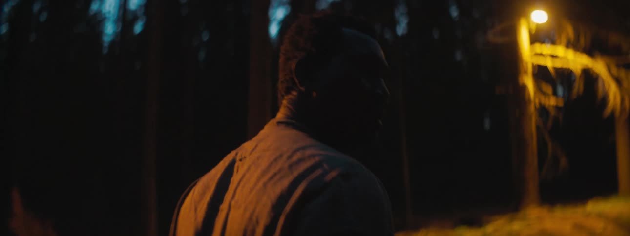 Depressed and sad man with a shirt walks on the road in through a forest at night