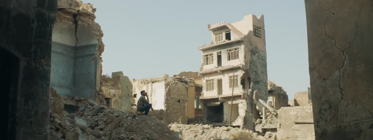A man sits by the ruins of the homes