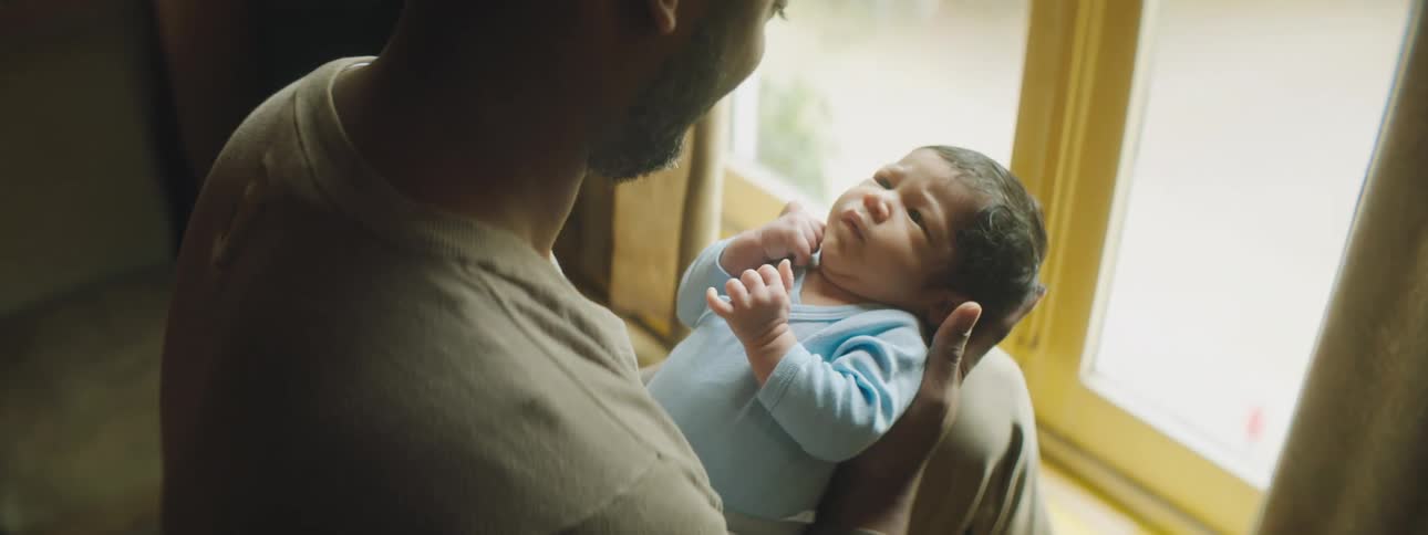 Man carefully holds baby sitting near glass doors