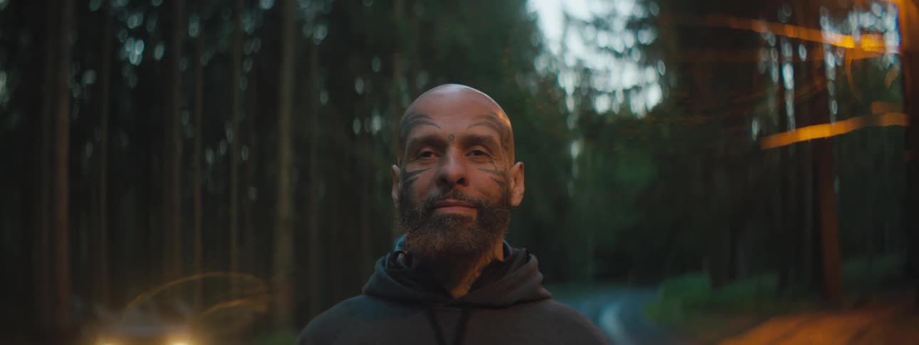 A man is standing outdoors in the woods