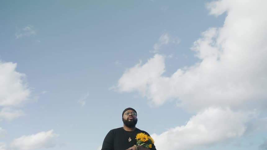 A man carries yellow flowers while walking outdoors during the day