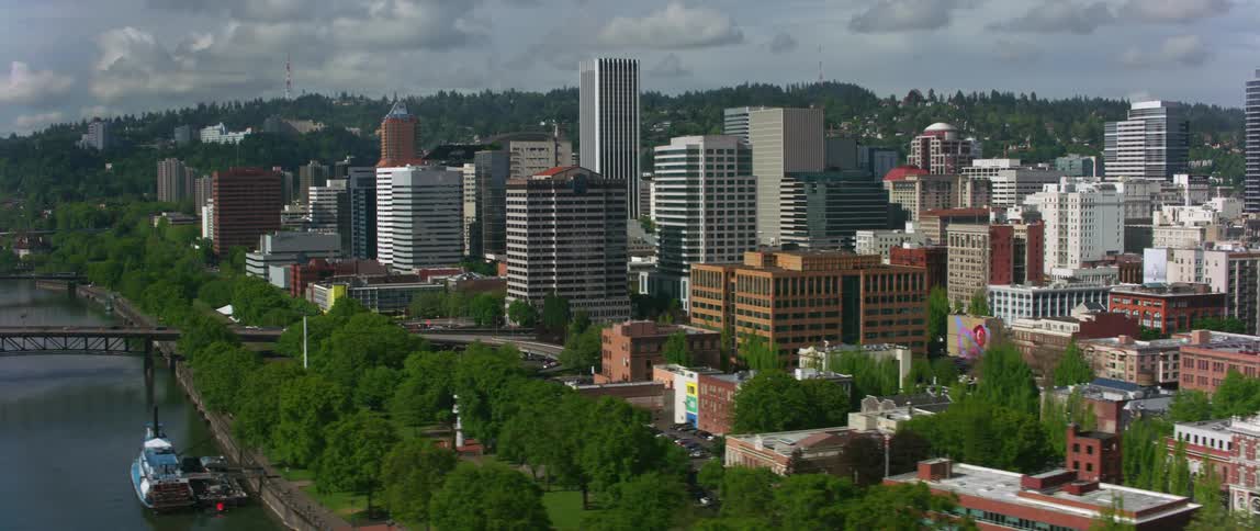 An aerial view of cars driving across a bridge in a city with office buildings