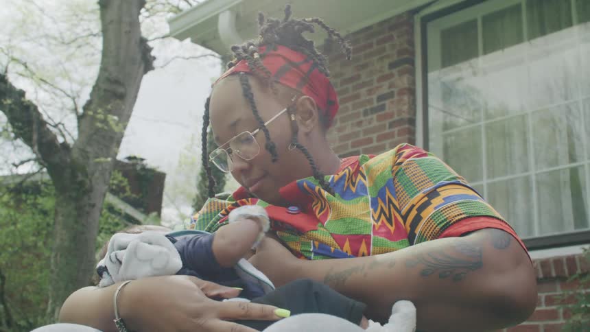 Tattooed mother sitting in the backyard breastfeeding a baby