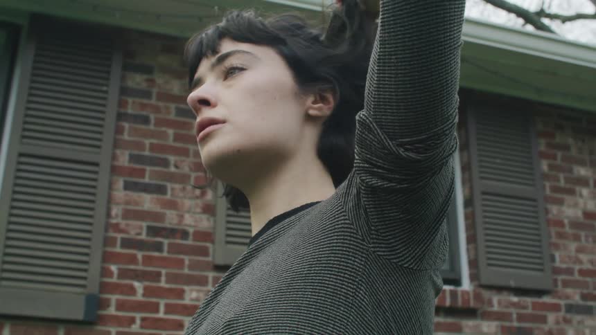 A woman is stretching and putting her fingers through her hair