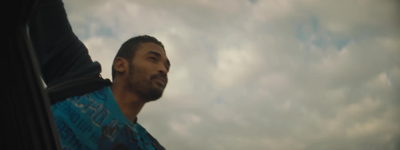 A man clothing blowing in the wind with the sky and clouds above