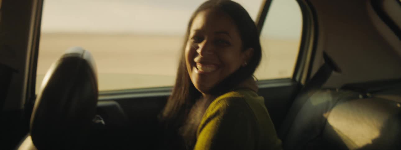 Woman sitting in back of car laughs