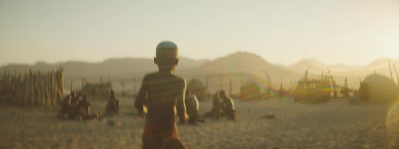 Small boy runs out of a hut in an aboriginal african village at sunset