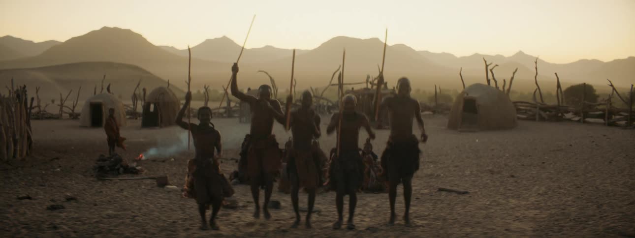A group of villagers cheer with sticks