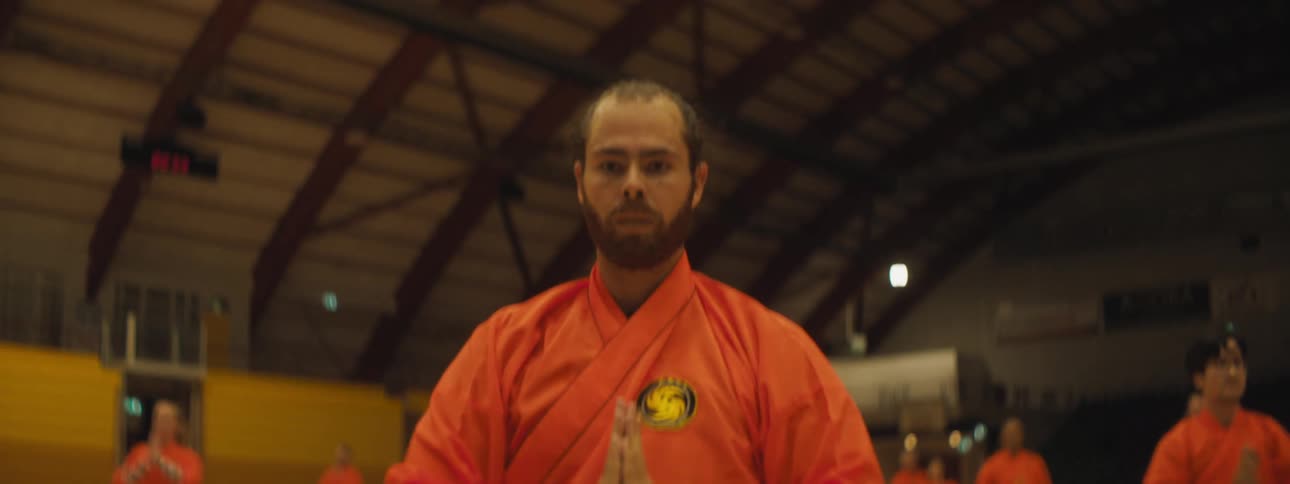 A man leads a group of people doing martial arts in a stadium
