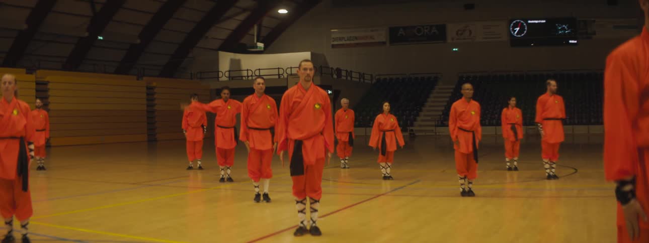 A group of people practice martial arts in a stadium