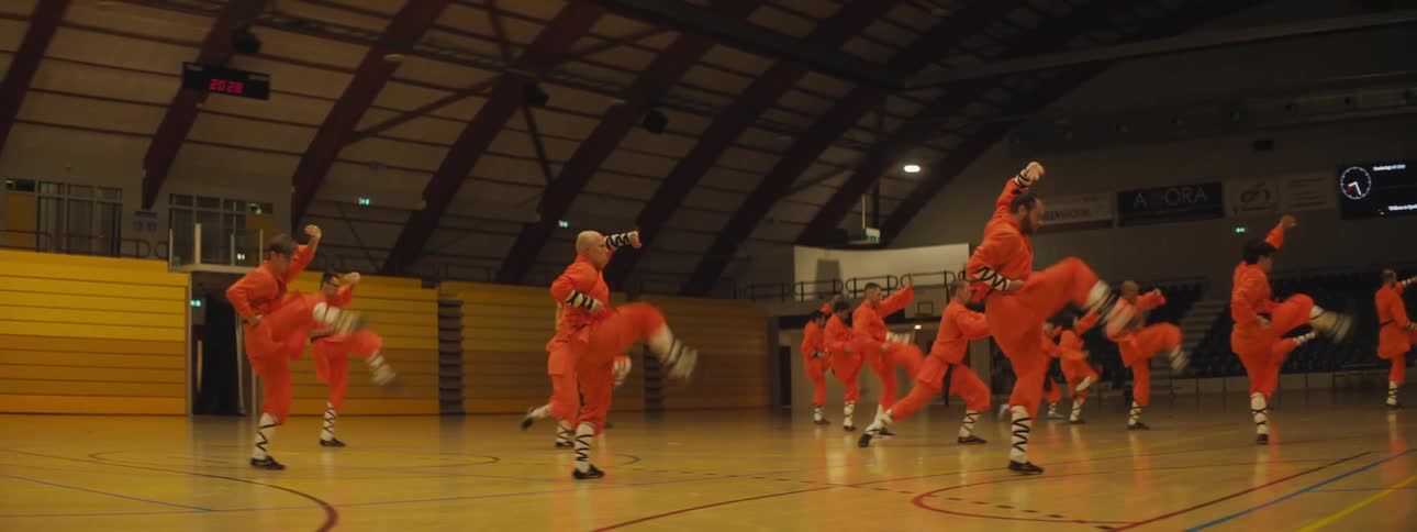 A group of martial artists practice their routine inside of a gymnasium