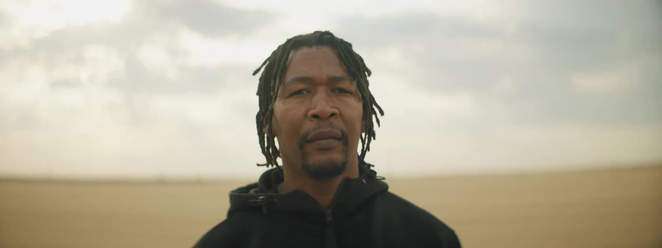 A man is standing in a rural area at dusk