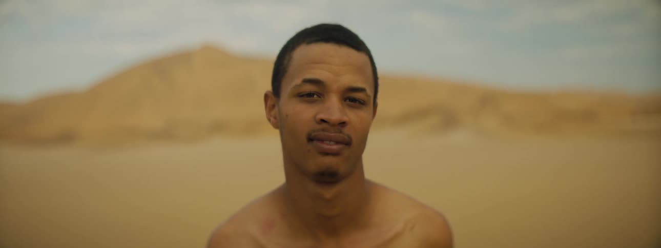 A man is standing outdoors in a desert area