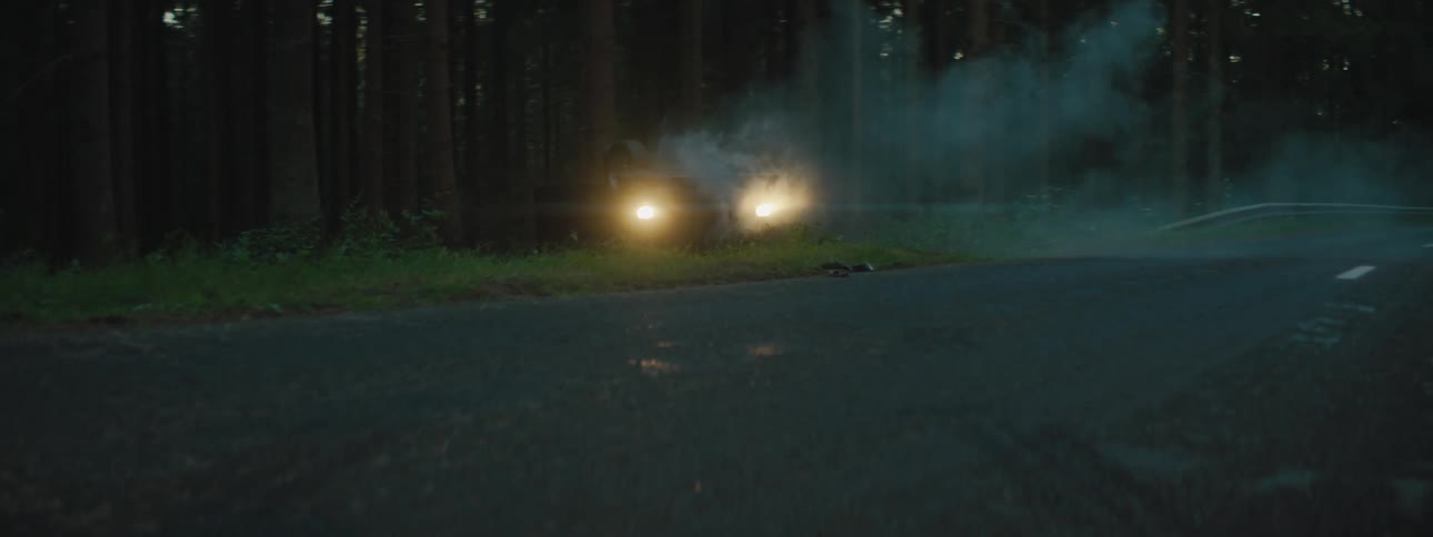 A car crash on the side of a forest road at night