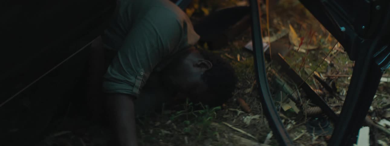 A man laying on the ground in a vehicle crash with blood