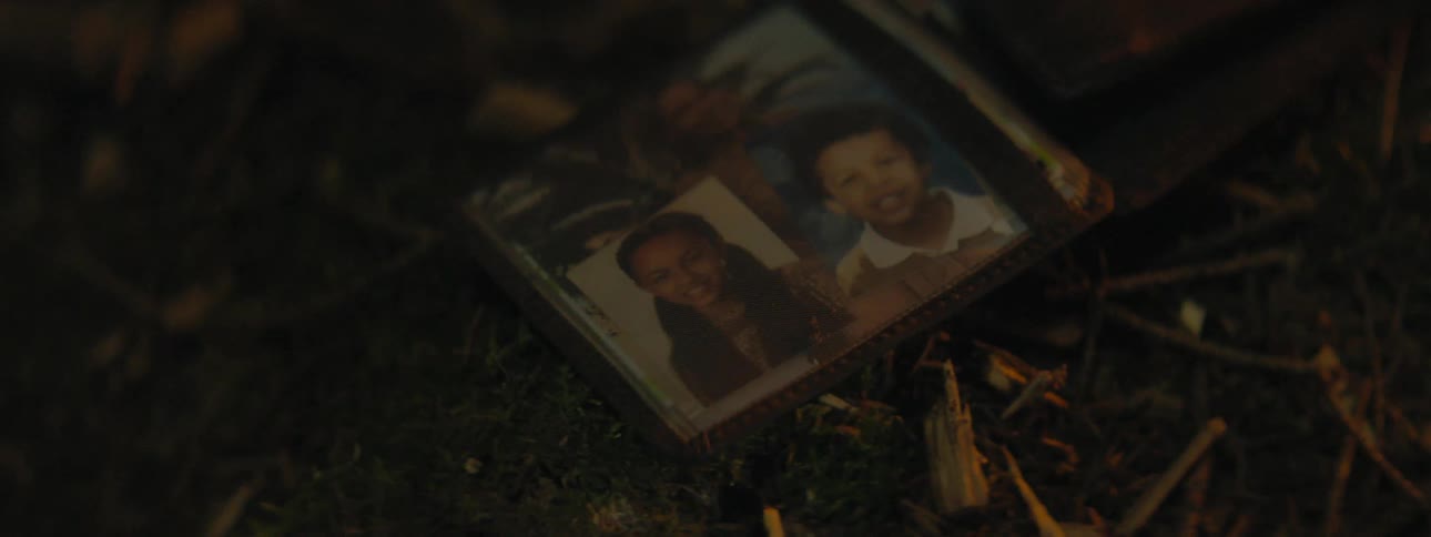 Small photographs of children in the photo pocket of a wallet lying on the ground