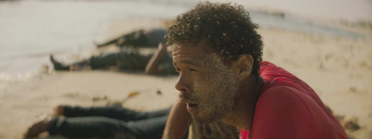 A man sitting on a beach with people laying on the sand in the background