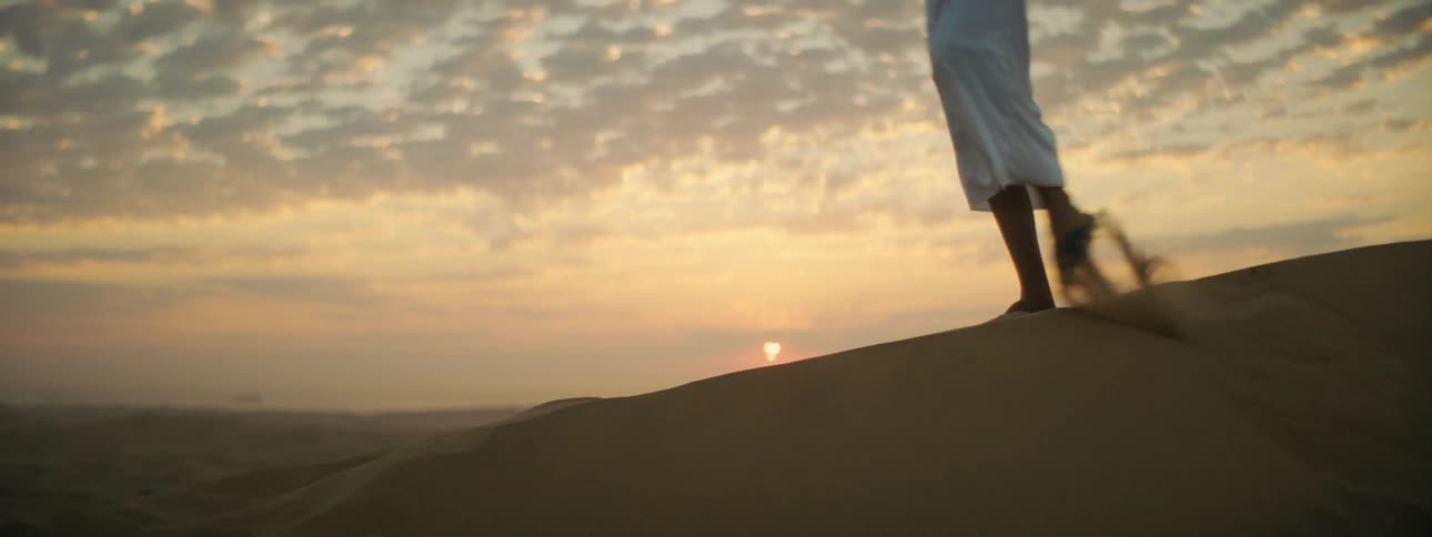 A person walks down a hill in a desert