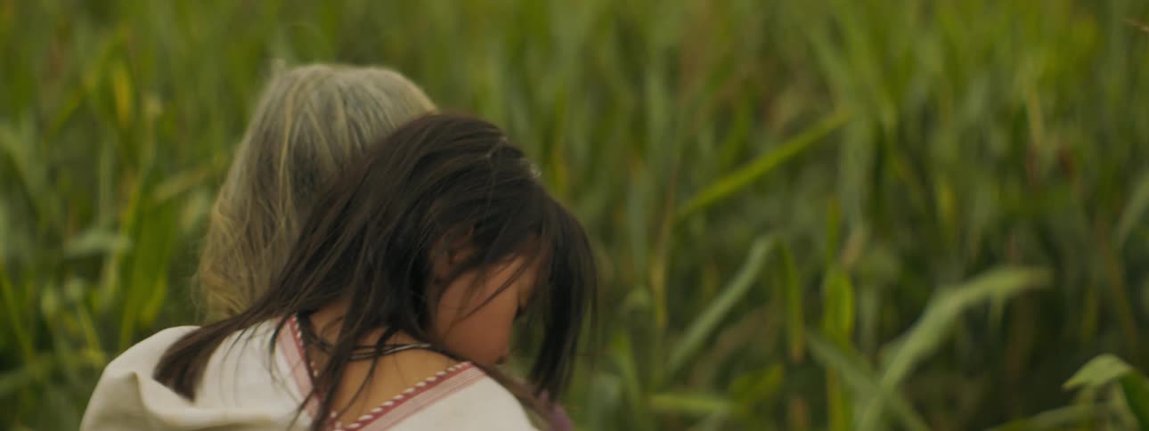 Adult carrying a child through a wheat field