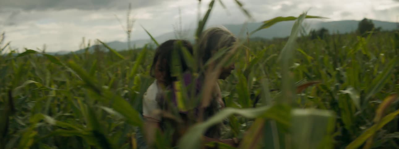 Grandmother carrying sleeping granddaughter through a grass field on her back