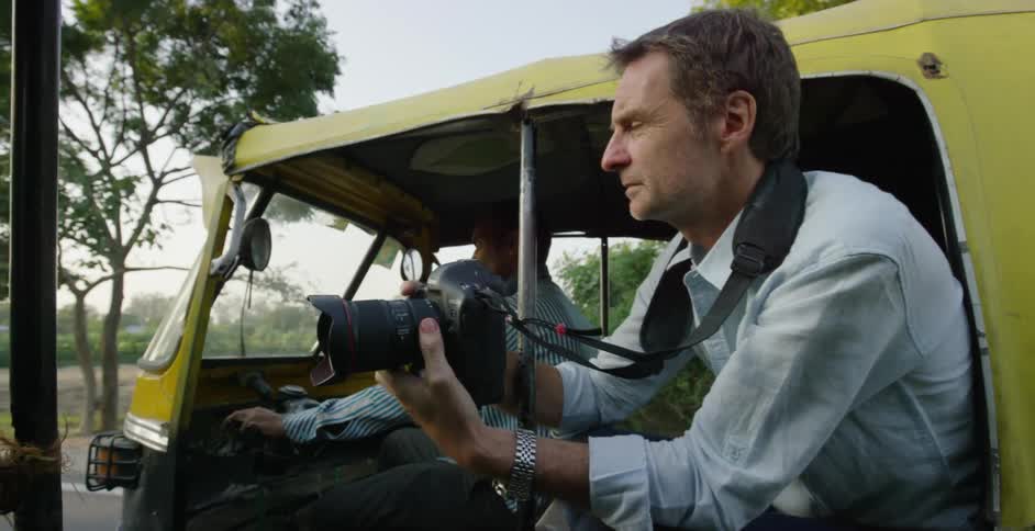 A man takes photographs while riding in a vehicle