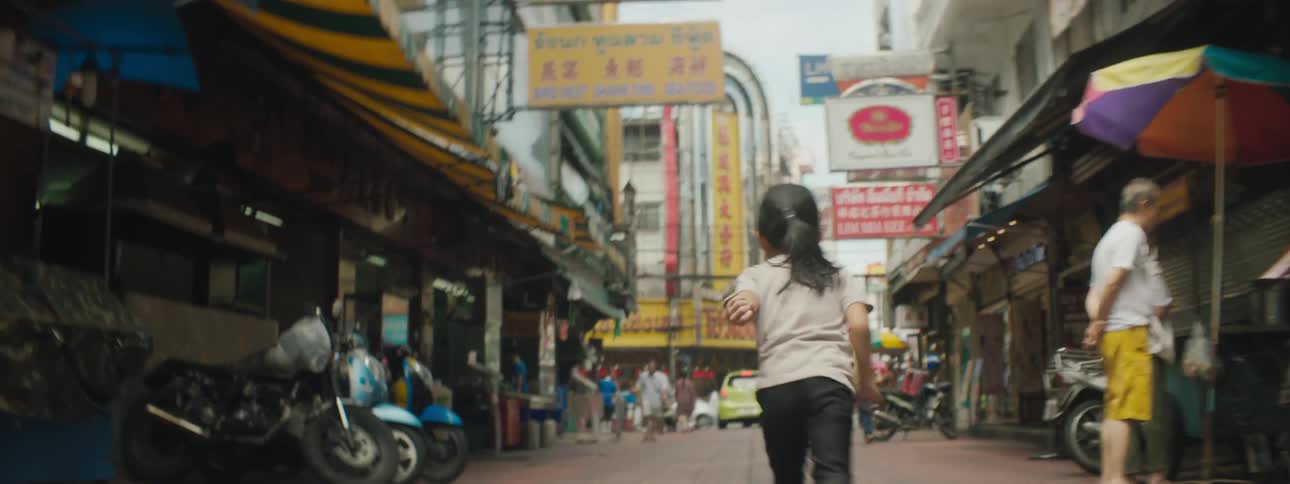 A young girl runs through a crowded town market seemingly by herself