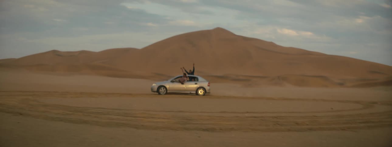 People hang out of the car cheering as they cheer