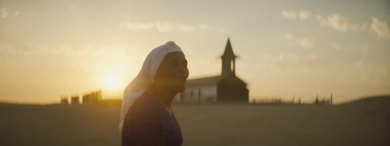 Black woman dancing happily in front of a church