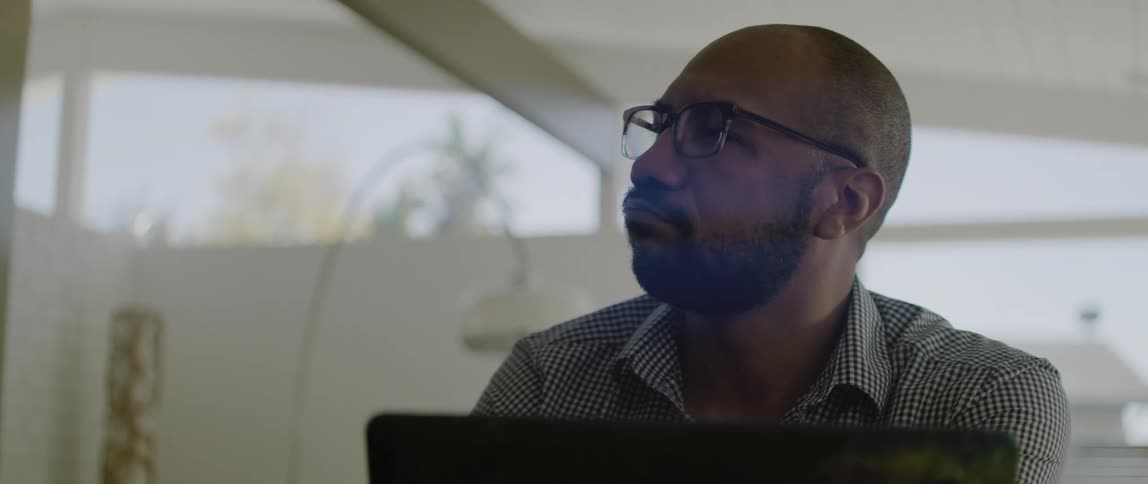 A man is sitting in front of a laptop in an office
