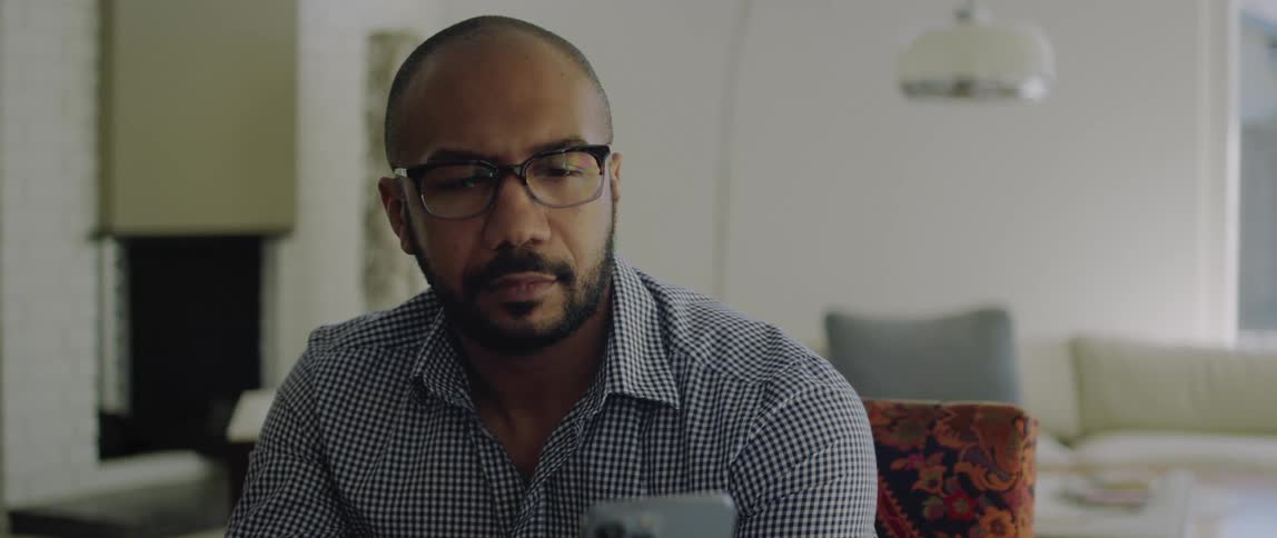 A man shakes his head and nods while talking on his smartphone