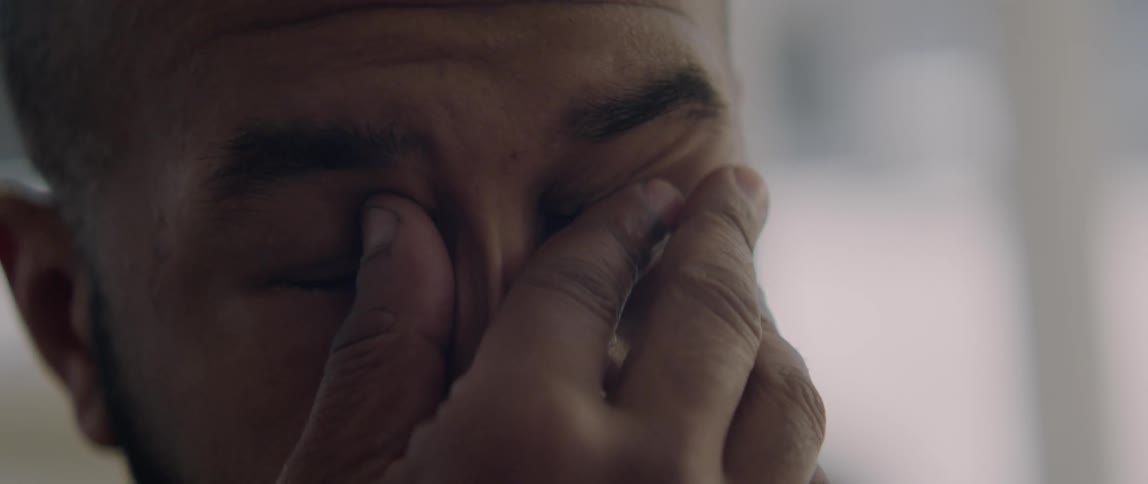 A man looks worried as he takes his glasses off and rubs his eyes