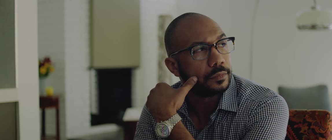 A man looks concerned as he sits in a house and thinks
