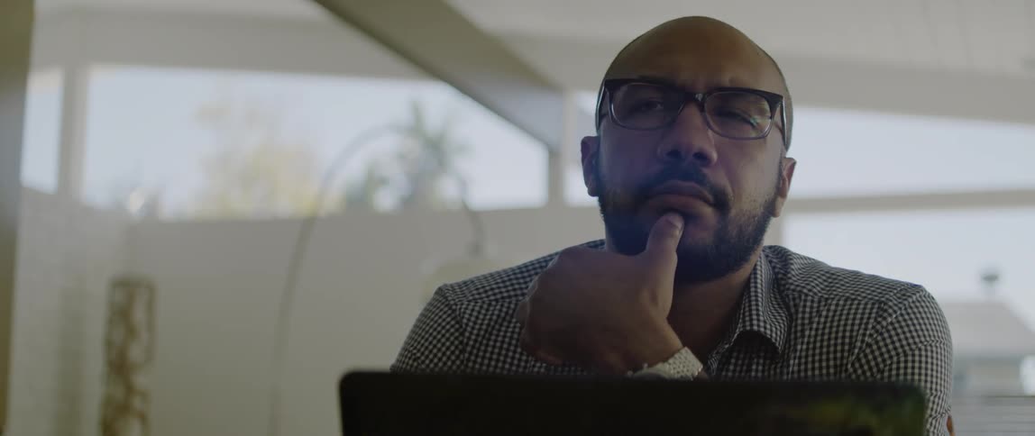 A man is sitting by his laptop indoors during midday