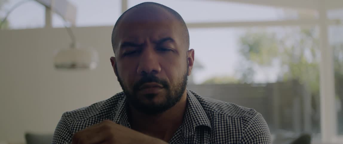 A man moves his glasses around as he sits and thinks in a house